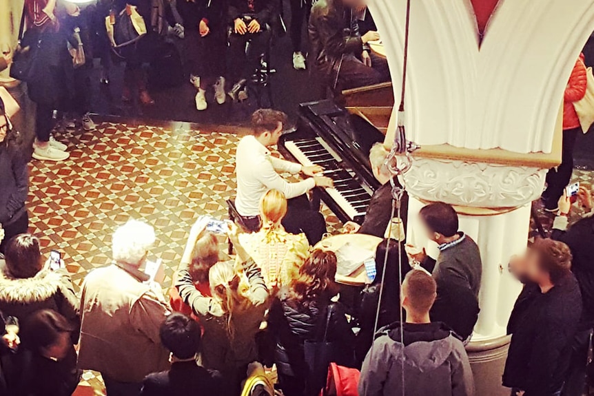 A man plays a piano in front of a crowd