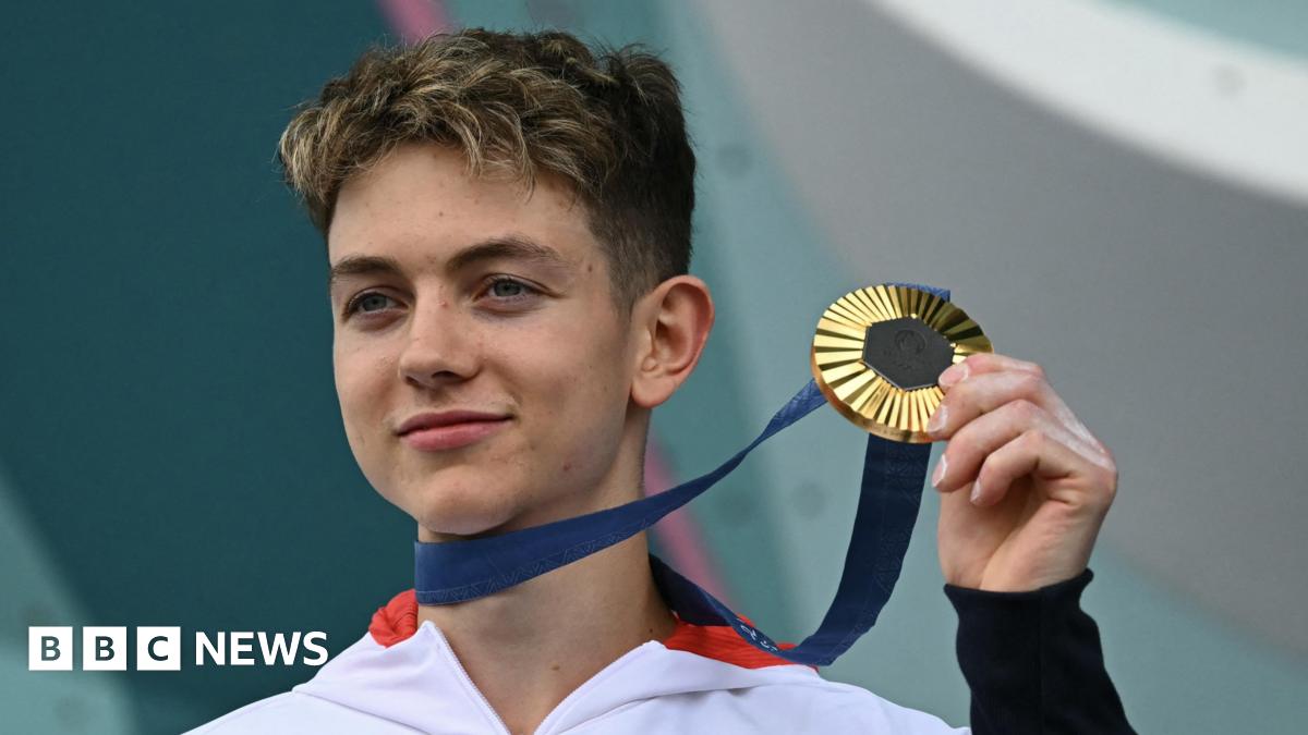 Toby Roberts holding up his Olympic gold medal.
