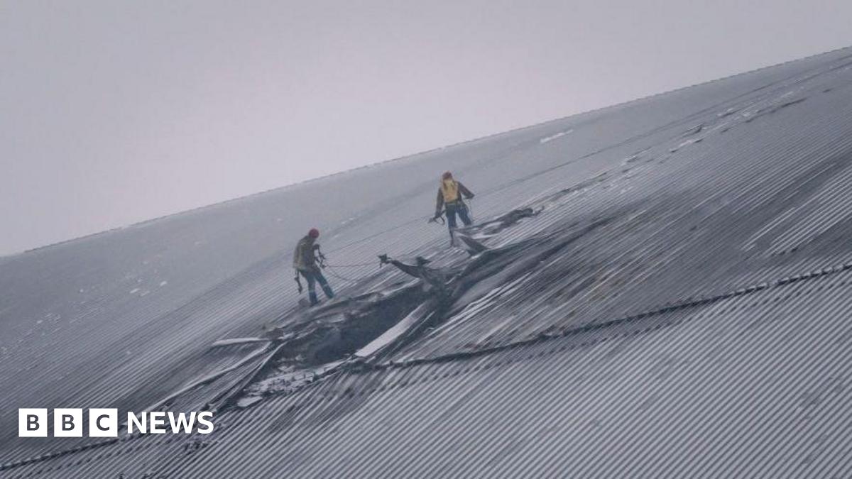 People inspect the damage to the radiation containment shield of Reactor 4 at the Chernobyl nuclear power plant following a drone strike