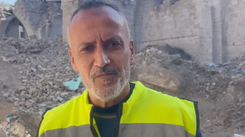 Hosni al-Mazloum stands in front of the ruins of the Great Omari Mosque in Gaza City, northern Gaza