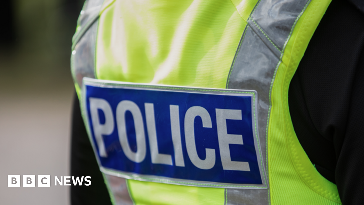 Stock image of the back of a police's florescent jacket that reads POLICE. The man wearing the jacket with a black t-shirt.