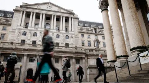 EPA People walk past the Bank of England in London, with pillars at the front of the Royal Exchange wrapped in fairy lights, on a grey day in December.