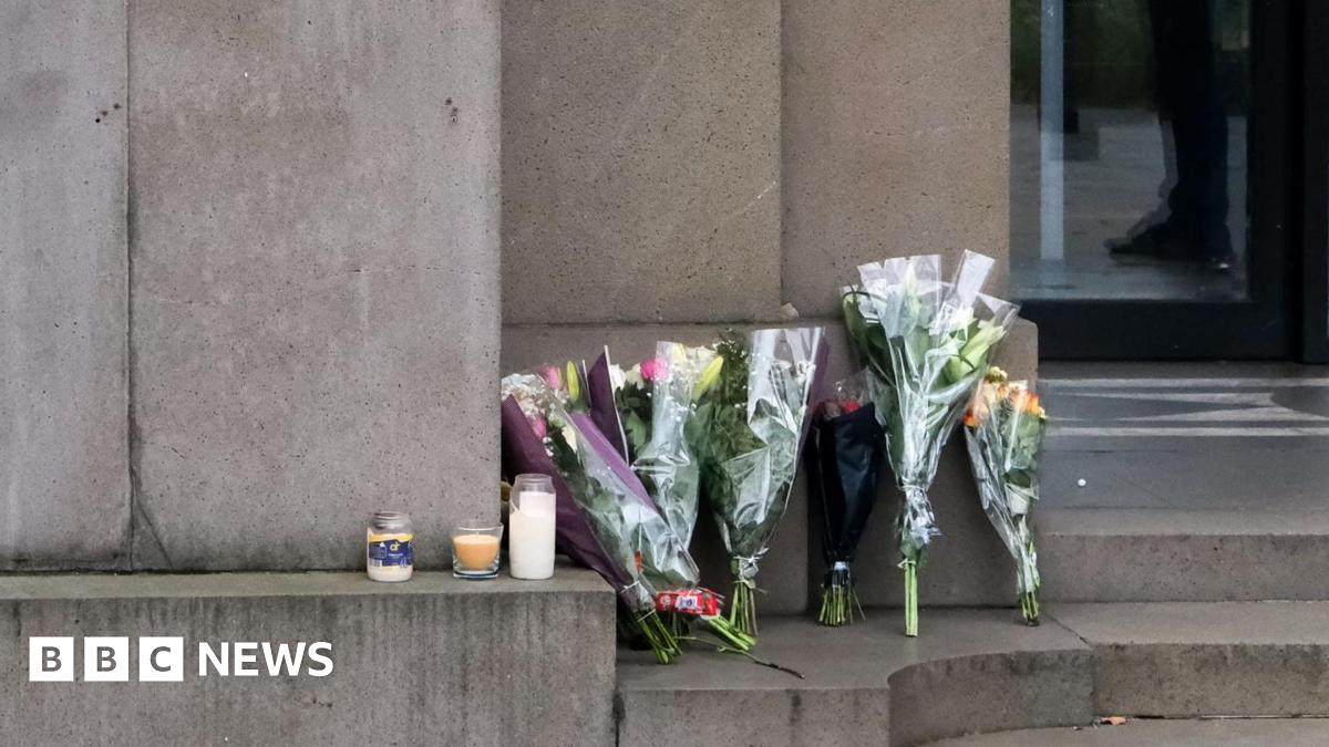 Flowers and candles at the Australian High Commission in London. There are several bunches of flowers and three candles at the top of stone steps.