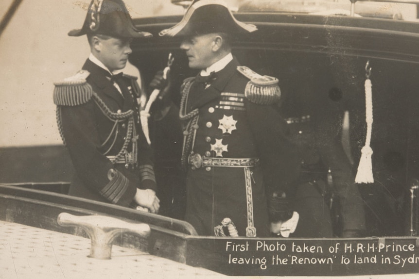 two men wearing military suits stand on a ship