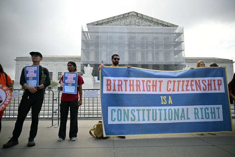 People hold a banner in front of a federal building.
