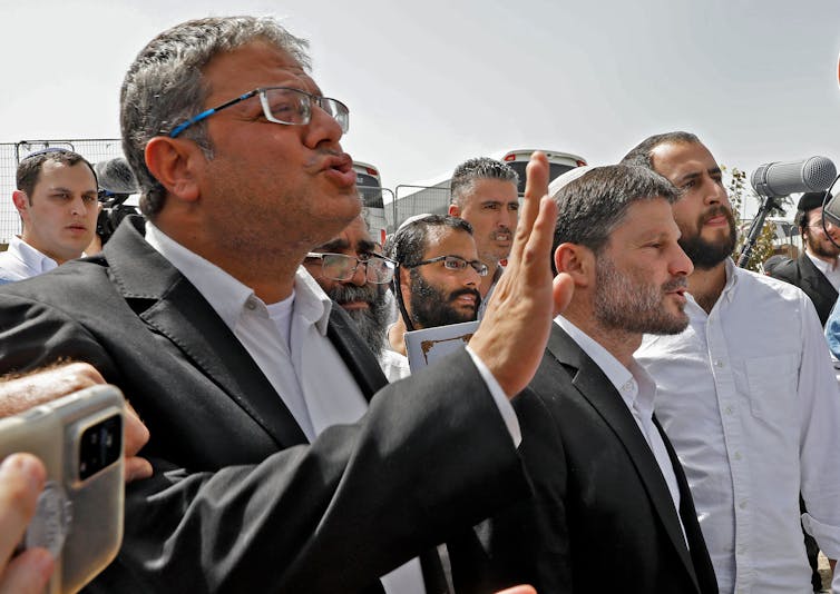 Men in suits gesticulate with their hands.