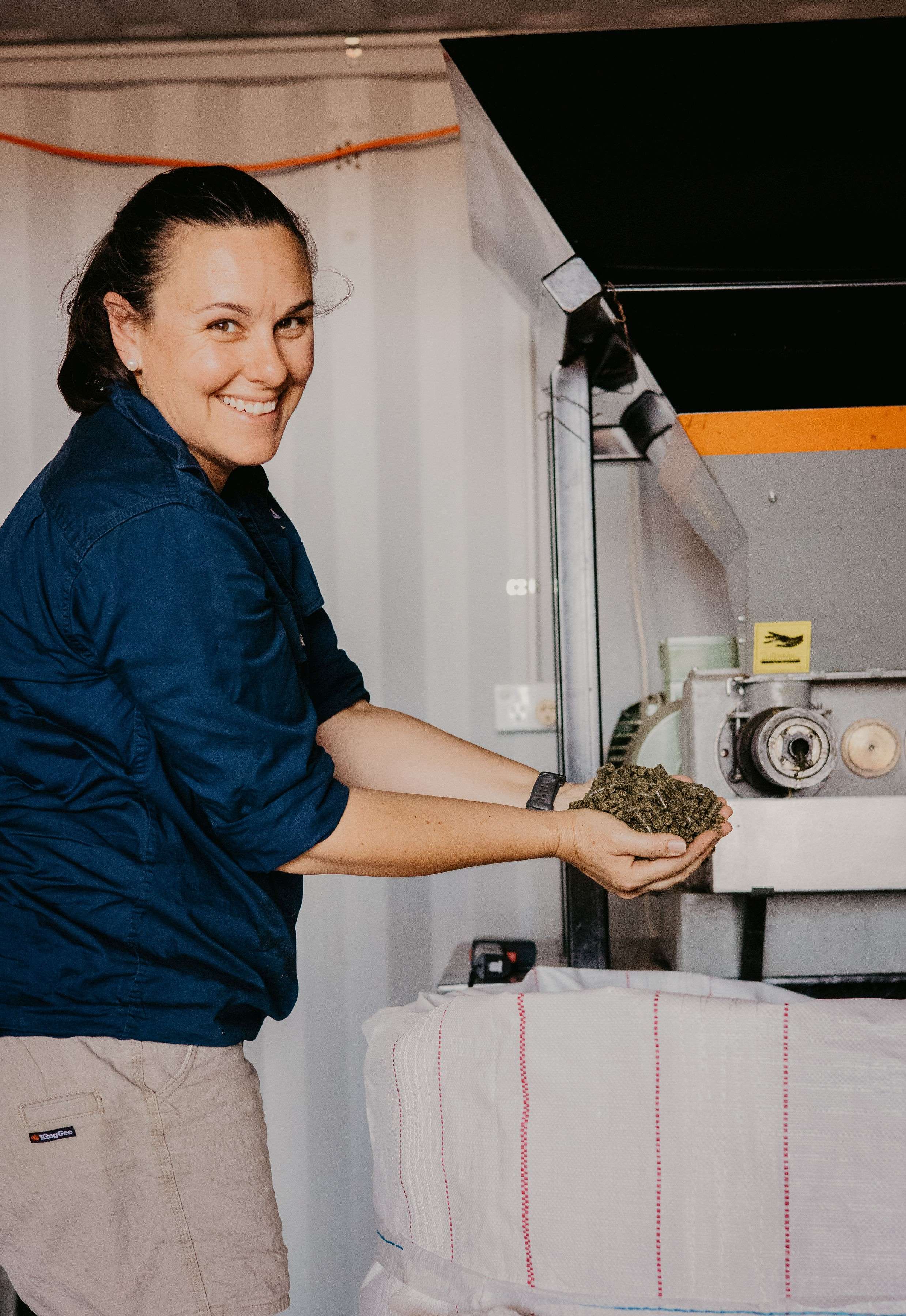 A woman holding canola near a machine.