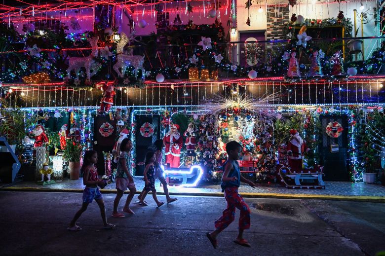 Children walk past a Christmas-themed house in Manila, on December 21, 2022.