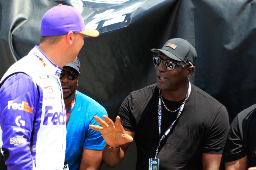 Michael Jordan talks with driver Denny Hamlin during qualifying for the NASCAR Cup Series Ally 400 in 2023.