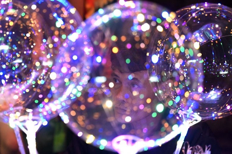 A man sells balloons as people attend a pre-dawn mass ahead of Christmas at a church in Las Pinas, Metro Manila, on December 16, 2023.