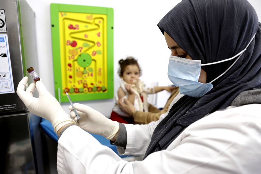 A child waits as a nurse prepares a dose of measles vaccine at a hospital in the Moroccan coastal city of Temara in February 2025. Measles and meningitis infections killed at least 100,000 children around the world in 2023, according to WHO data.