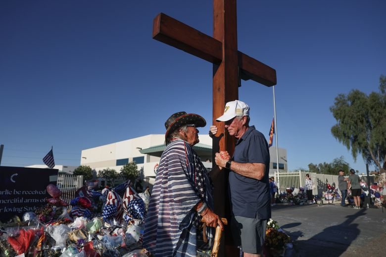 Maggie Mae Roddy, left, prays with Beazley at the makeshift memorial for Charlie Kirk outside the headquarters of Kirk's organization, Turning Point USA, on September 19 in Phoenix.