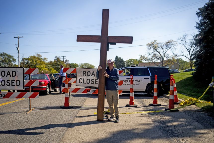 Beazley stands with the cross near the site of the shooting and fire at The Church of Jesus Christ of Latter-day Saints in Grand Blanc, Michigan, on September 29.