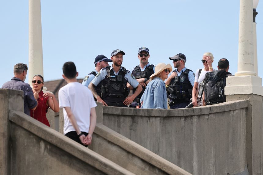People and the police are seen on the footbridge that was used by the father-and-son gunmen during the December 14 Bondi Beach shooting, in Sydney, on December 18, 2025.