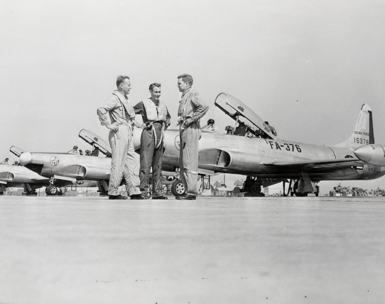 Members of the 142nd Fighter Interceptor Squadron stand on the flight line in front of their F-94s and discuss flying over Washington, DC, in pursuit of elusive 