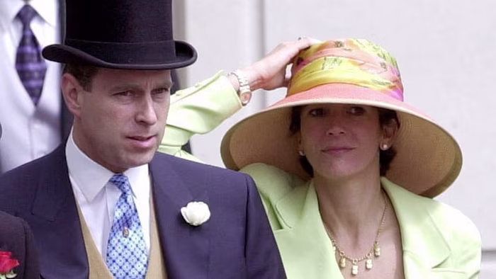 Prince Andrew, Duke of York, in formal attire with a top hat, stands beside Ghislaine Maxwell, who wears a large colorful hat and light green jacket.