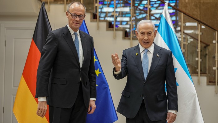 Friedrich Merz stands next to Benjamin Netanyahu in front of German, EU and Israeli flags