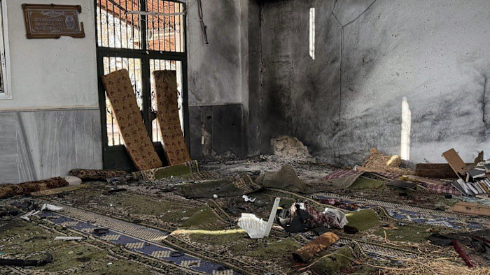 Debris, damaged carpets, and blackened walls inside the Imam Ali bin Abi Talib Mosque after an explosion.