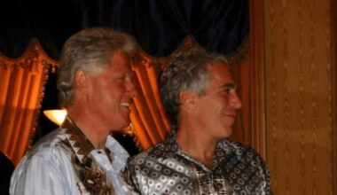 Bill Clinton stands next to Jeffrey Epstein. Both are smiling and wearing patterned shirts indoors.