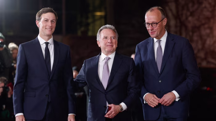 Friedrich Merz, right, greets Jared Kushner, left, and Steve Witkoff, centre, as they arrive, all three wearing dark suits and ties.
