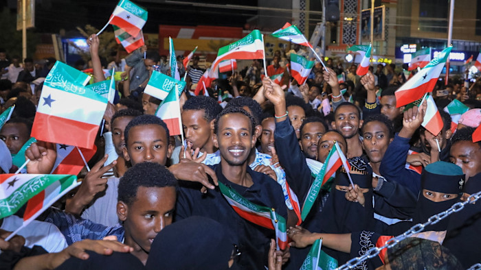 People waving Somaliland flags and celebrating in downtown Hargeisa at night.