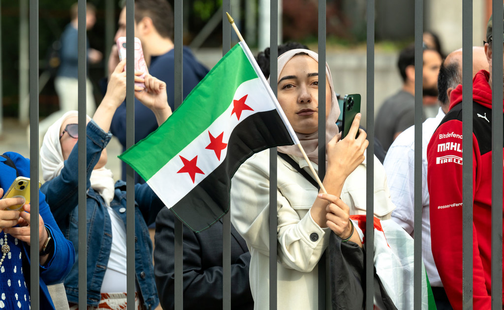 A woman holds the new Syrian flag outside UN Headquarters in New York.