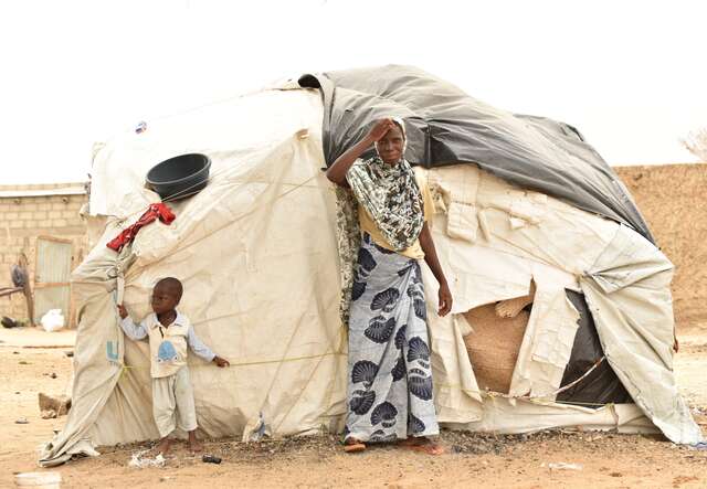 A mother and her son stand outside their temporary shelter in Burkina Faso.
