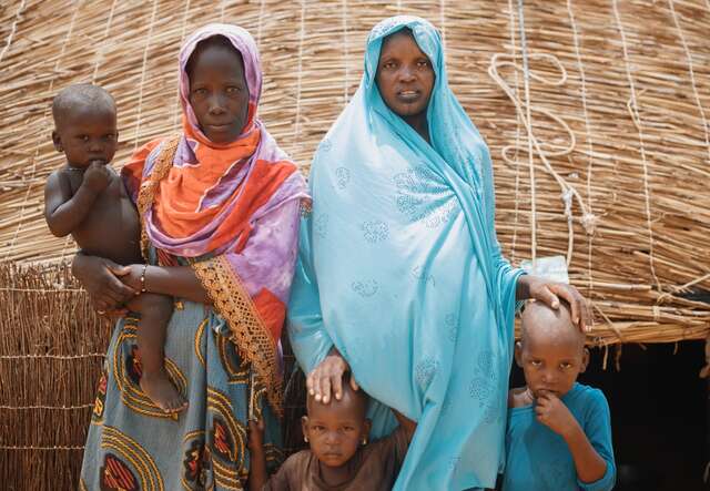 Two women and their children stand outside their home in Mali.