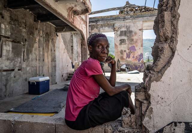 A woman poses for a photo in the ruins of a structure in Haiti.