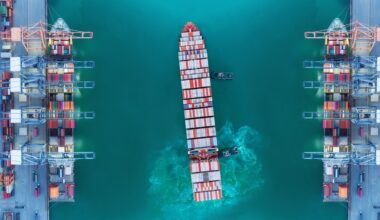 Container ship moving past seaport warehouse.