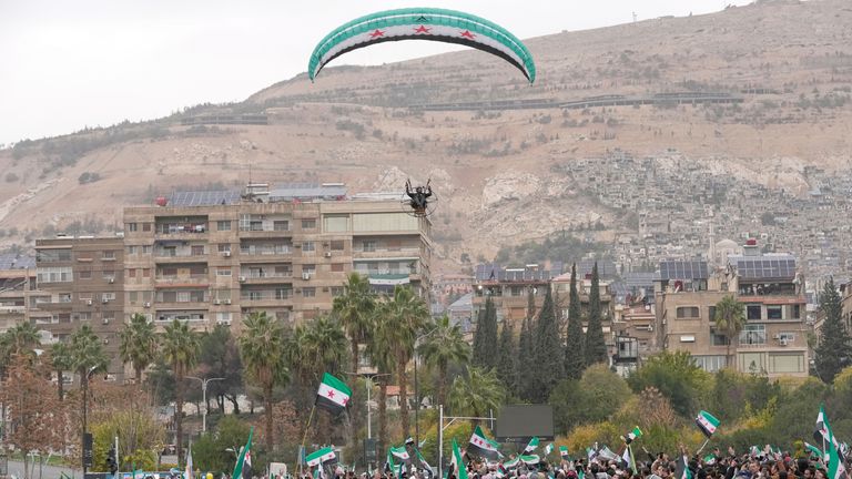 A paraglider flies over the crowds in Damascus. Pic: AP