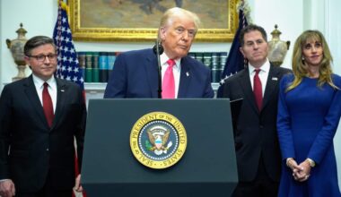 Donald Trump speaks at a podium inside the White House, with two men and a woman standing next to him.