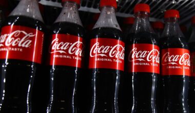 Row of Coca-Cola bottles lined up in fridge.