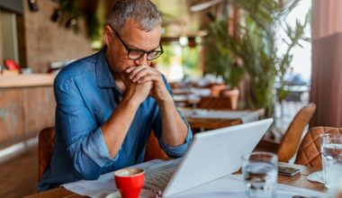Investor with hands clasped looking at laptop screen.