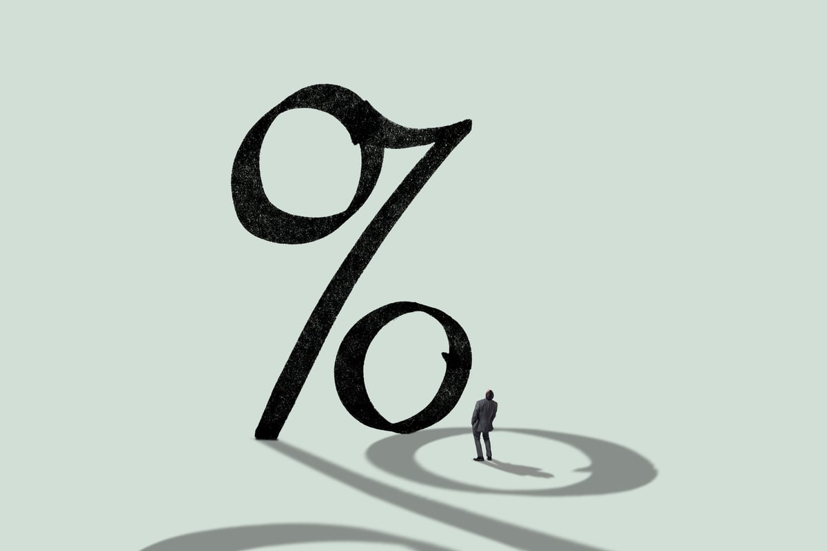 A person looking up at a large percent sign.