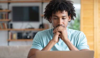 A person looks at a laptop with a thoughtful look on their face.