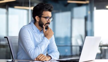 A person sitting at a desktop looking at a laptop screen.