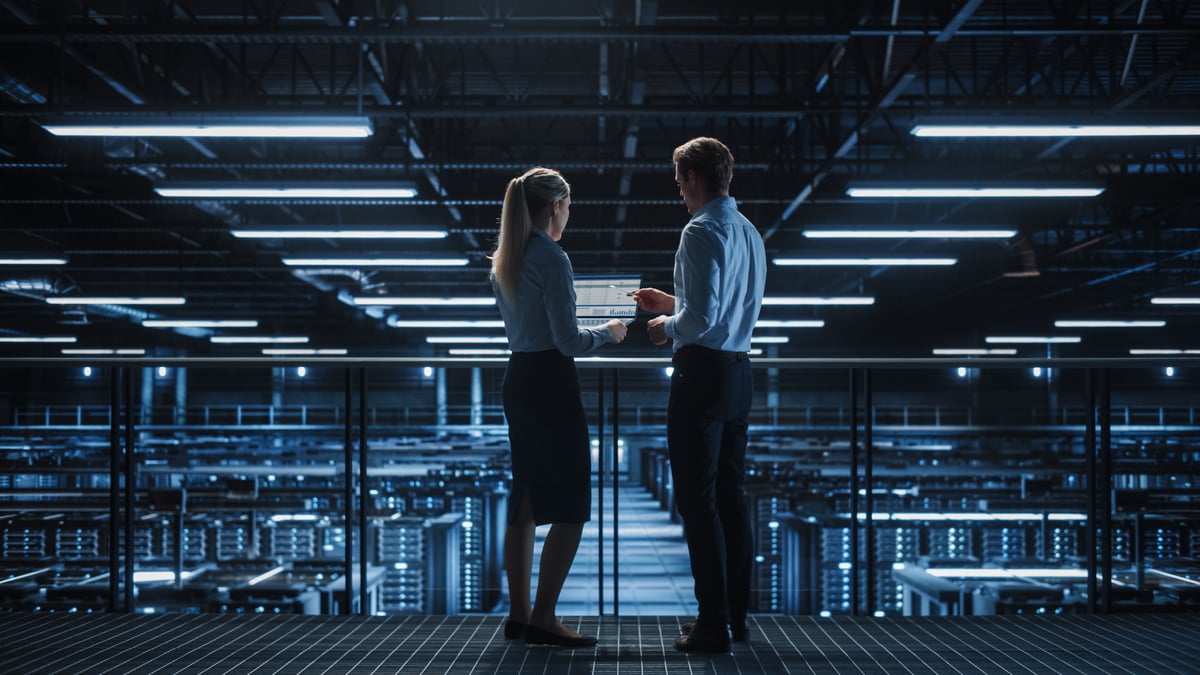 Two people are working inside a data center.