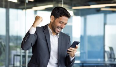 An excited person looking at their smartphone and pumping their fist.