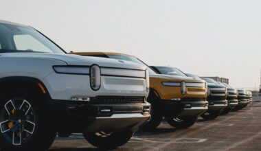 Line of Rivian trucks in a parking lot.