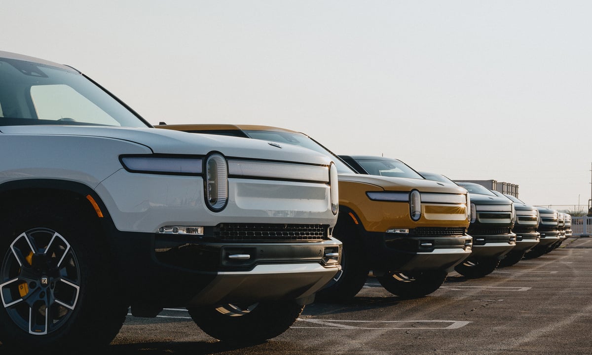 Line of Rivian trucks in a parking lot.