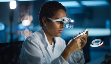 Person in a white lab coat working with a circuit board.