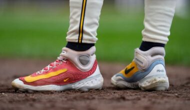 Baseball player wearing two different Nike shoes, standing in the infield.
