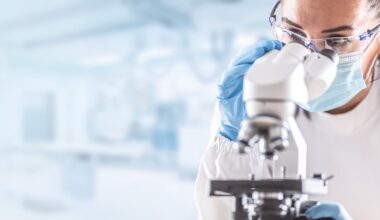 Person in a lab gazing into a microscope.