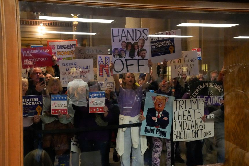 Protesters stand outside as the Senate gathers during mid-cycle session to vote on redistricting, in the Senate Chambers of the Indiana Statehouse in Indianapolis, on Thursday, December 11, 2025.