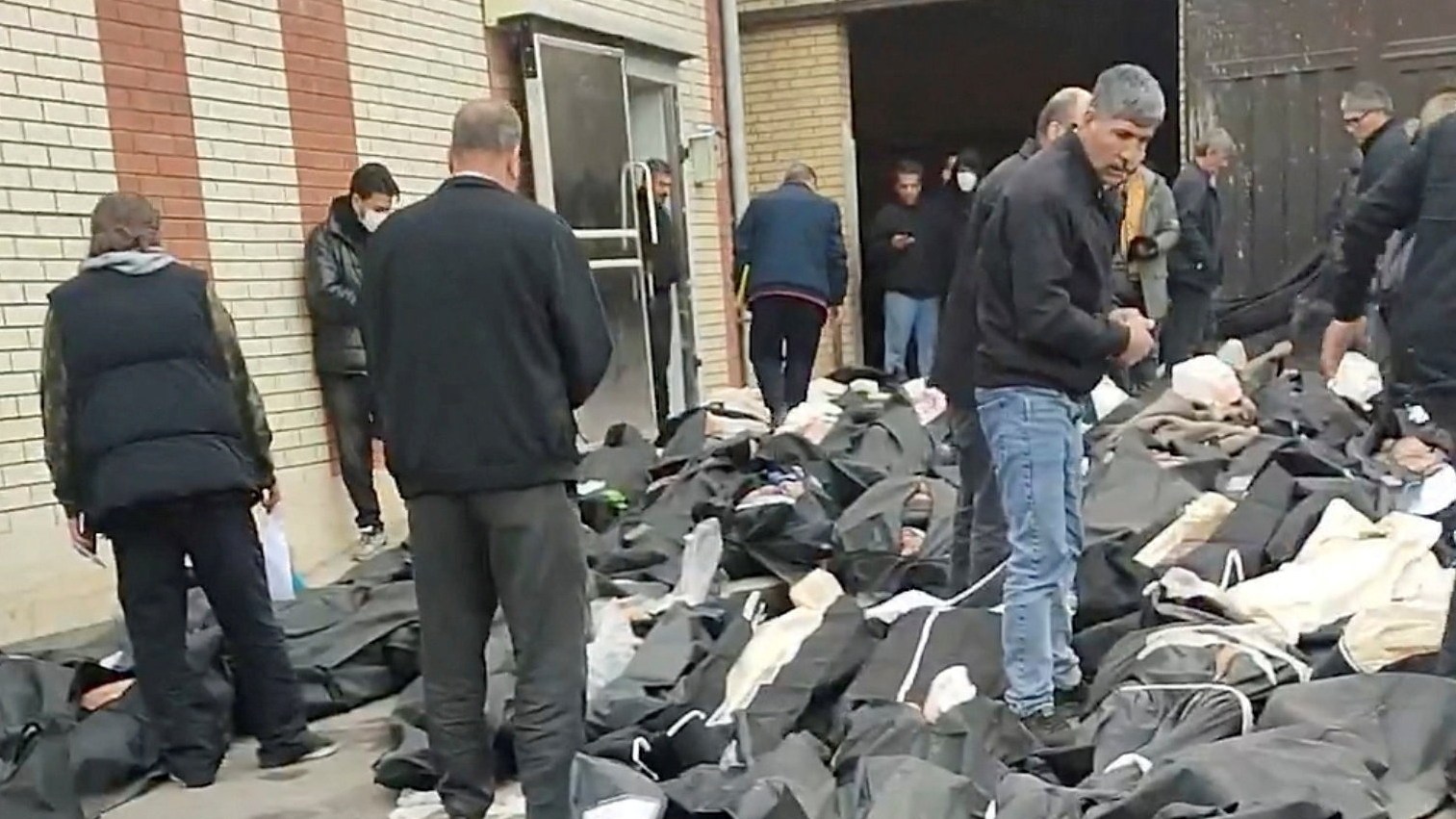 Bodies in body bags lie on the ground as people stand amid the scene outside Kahrizak Forensic Medical Centre in Tehran, Iran.