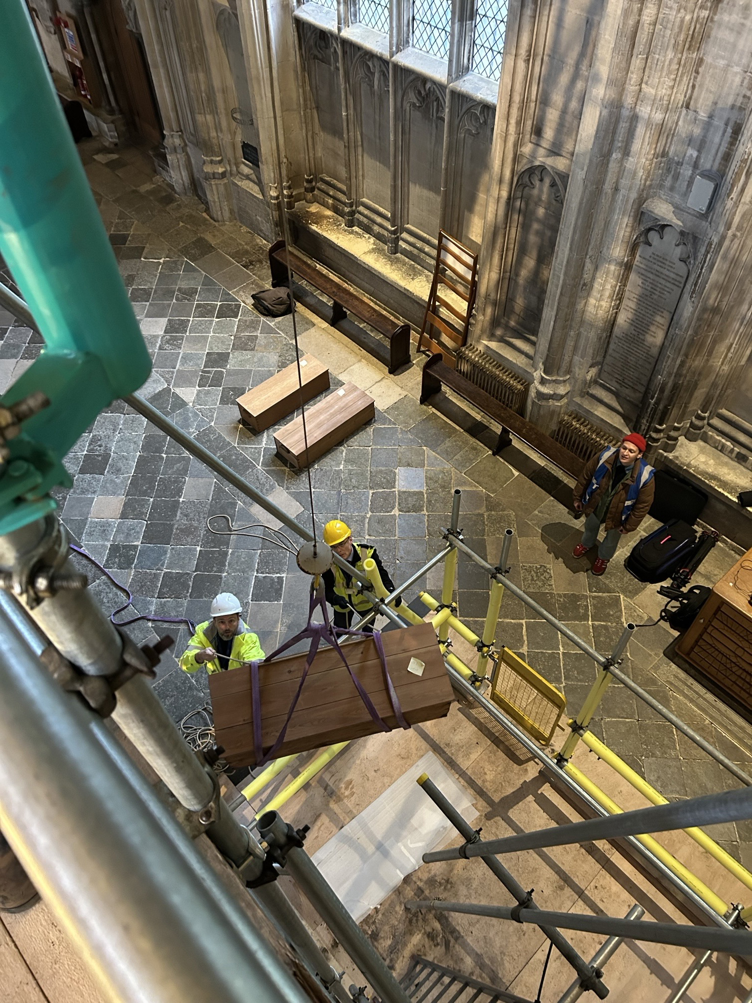 Workers reinterring Anglo-Saxon royal bones in Winchester Cathedral, using a winch to lift a box of bones to a mortuary box.