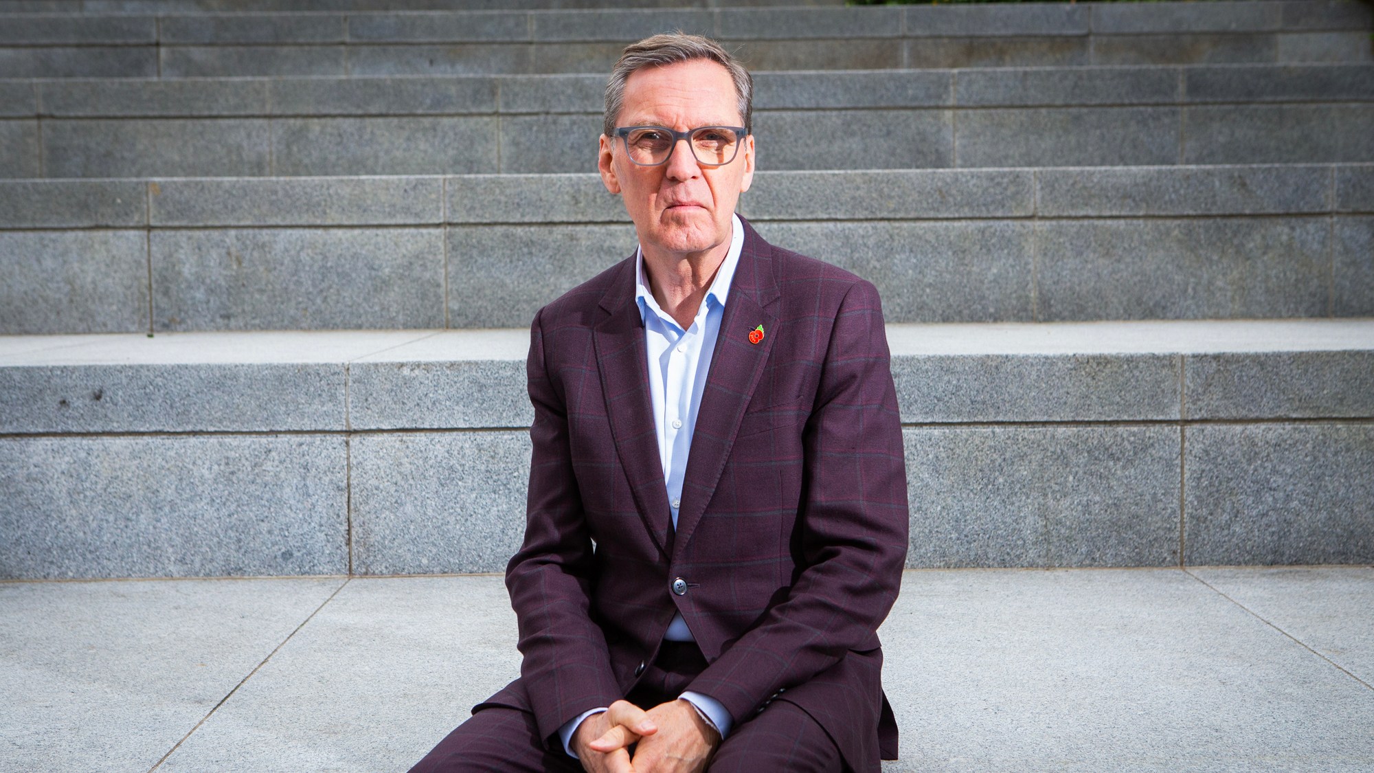 Former health secretary Alan Milburn sitting on concrete steps.