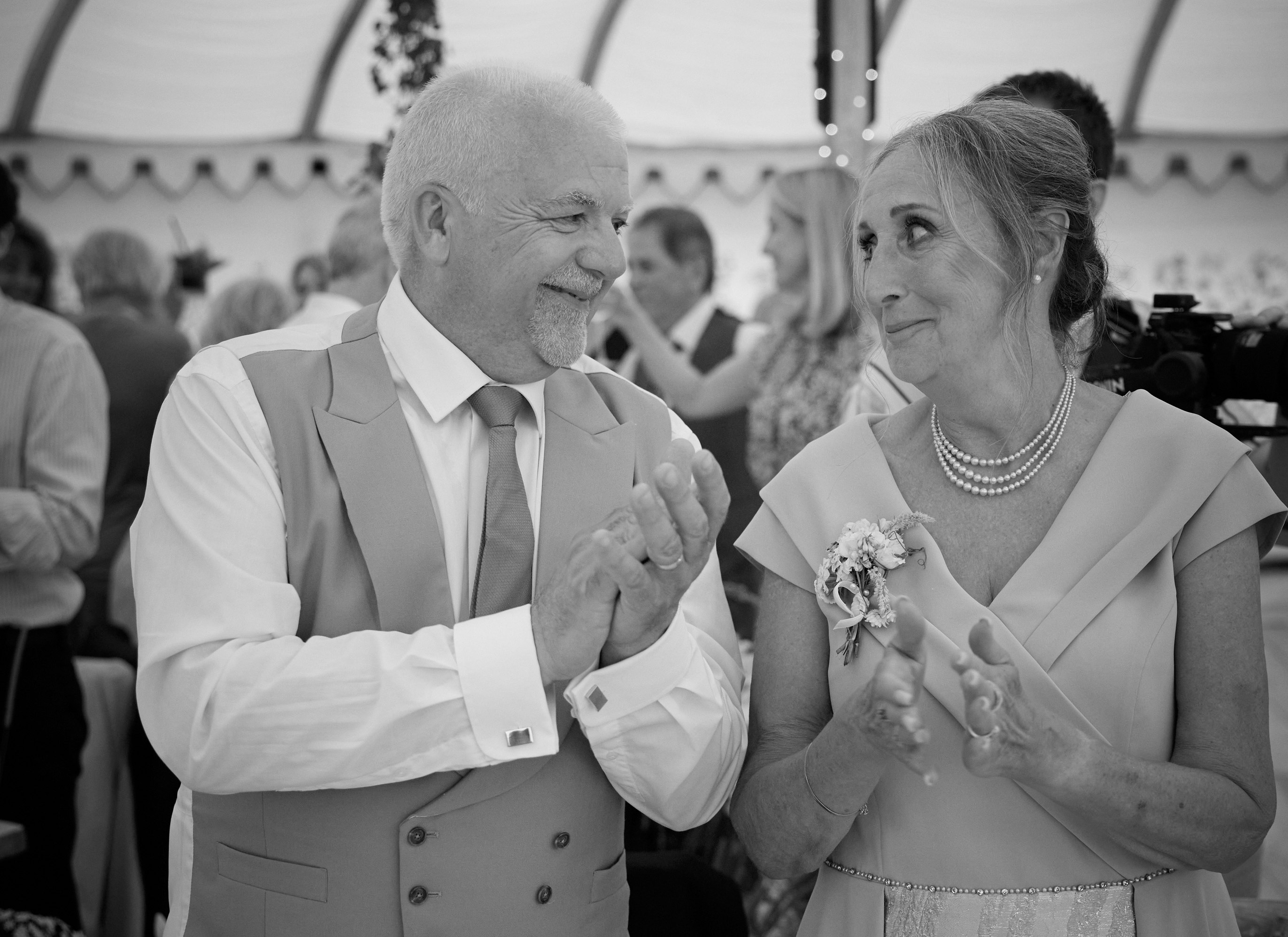 Karen Pooley and her husband Andrew smiling and clapping at a table.