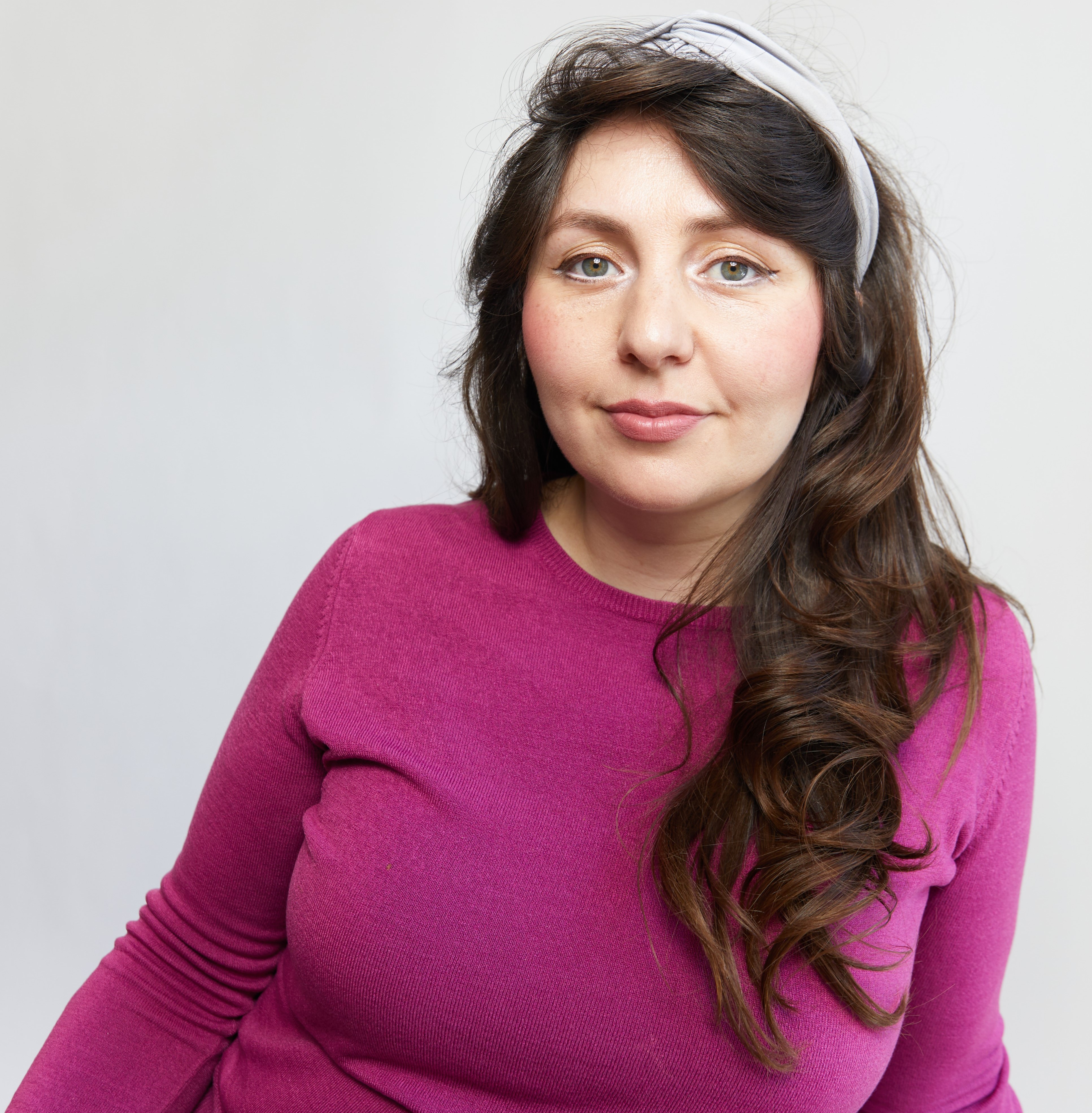 Charlotte Fischer, co-founder of Love & Power, wearing a magenta sweater and a light-colored headband.